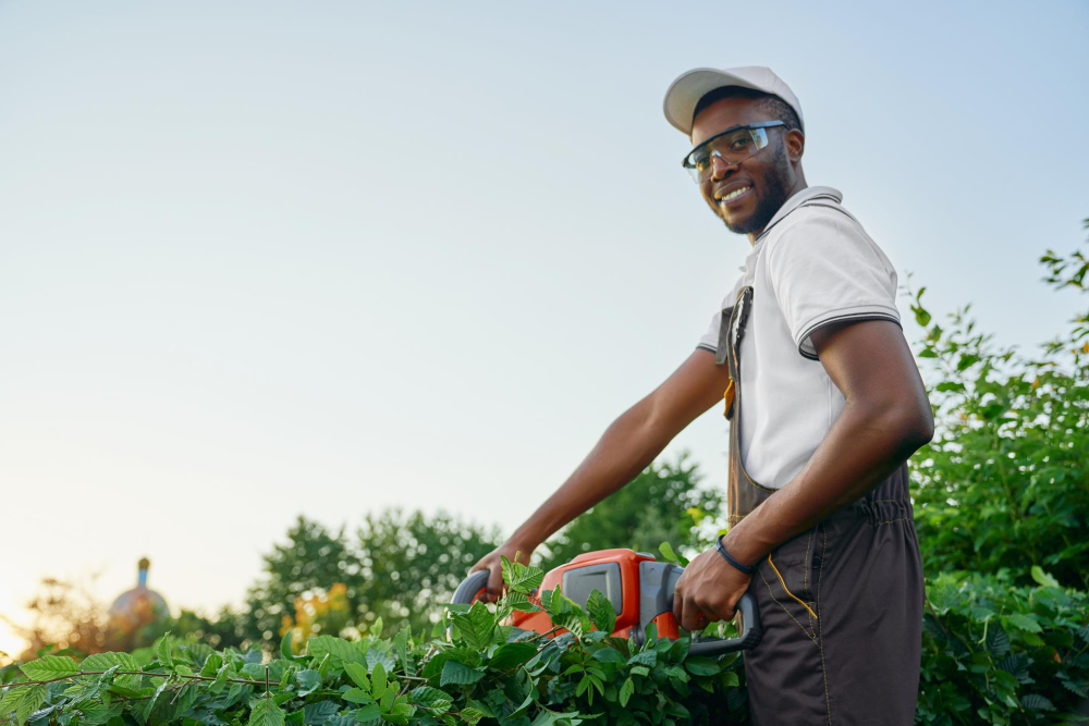 happy-african-man-trimming-bushes-with-gas-powered-clipper